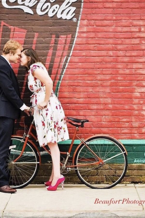 Lady on a bike leaning in to kiss her fiancé